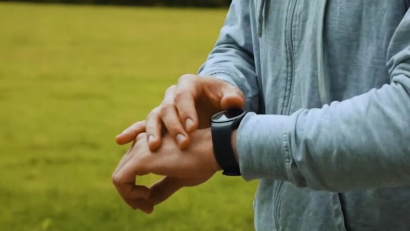 A Person Checks Their Smartwatch Timer, Preparing to Assess Cardiovascular Endurance with A Timed Run in An Open Field