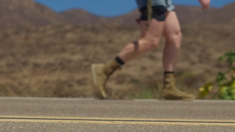 A Person Wearing Military Boots Jogs Along a Road in A Desert-Like Environment, Working to Boost Speed and Strength for The Military Running Program