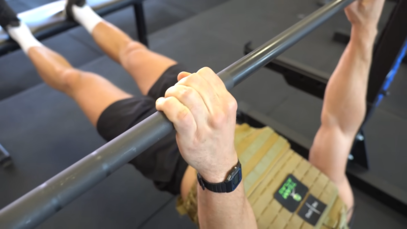 A Person Performs an Inverted Row While Wearing a Weighted Vest, Incorporating Cross-Training Exercises to Support Injury Prevention During the 12-Week Military Running Program