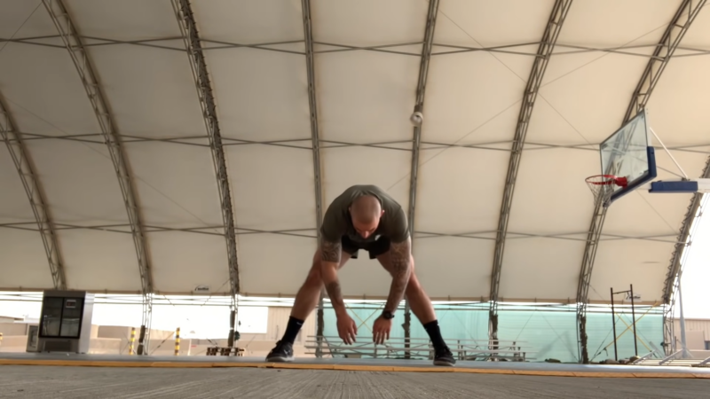 A Soldier Performs a Stretching Exercise Under a Large Covered Gym Area, Highlighting the Focus on Longevity and Recovery in Military Tactical Fitness