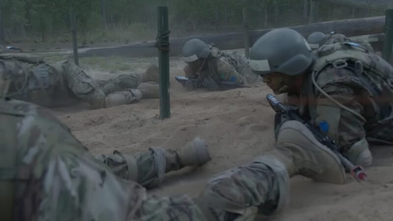 Soldiers Crawl Through Sand Under Low Obstacles During a Tactical Training Exercise, Highlighting Techniques Used to Enhance Combat Skills