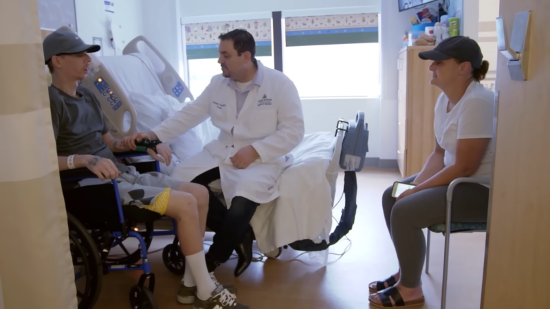 A Doctor Talking to A Gunshot Survivor in A Wheelchair During a Hospital Recovery