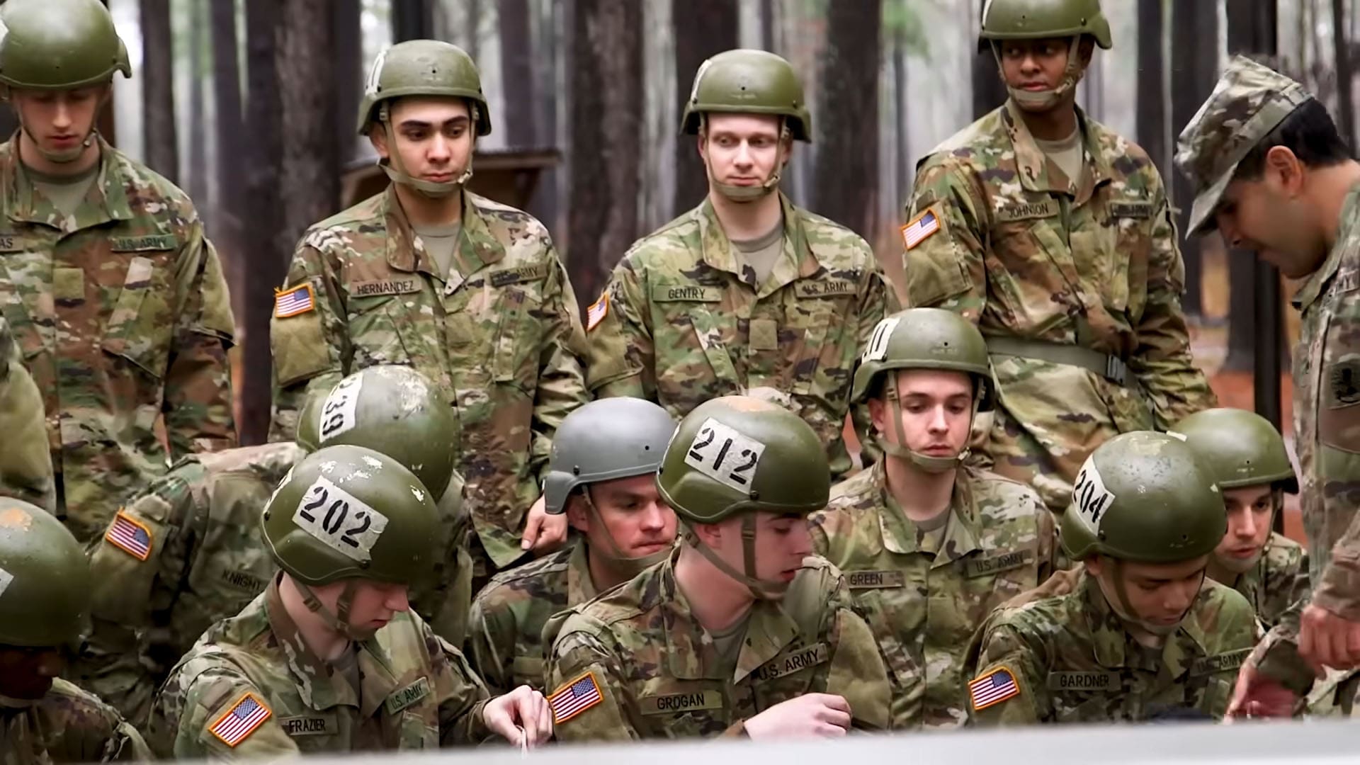 Group of U.S. Army soldiers in camouflage uniforms and helmets gathered during a training session in a forest