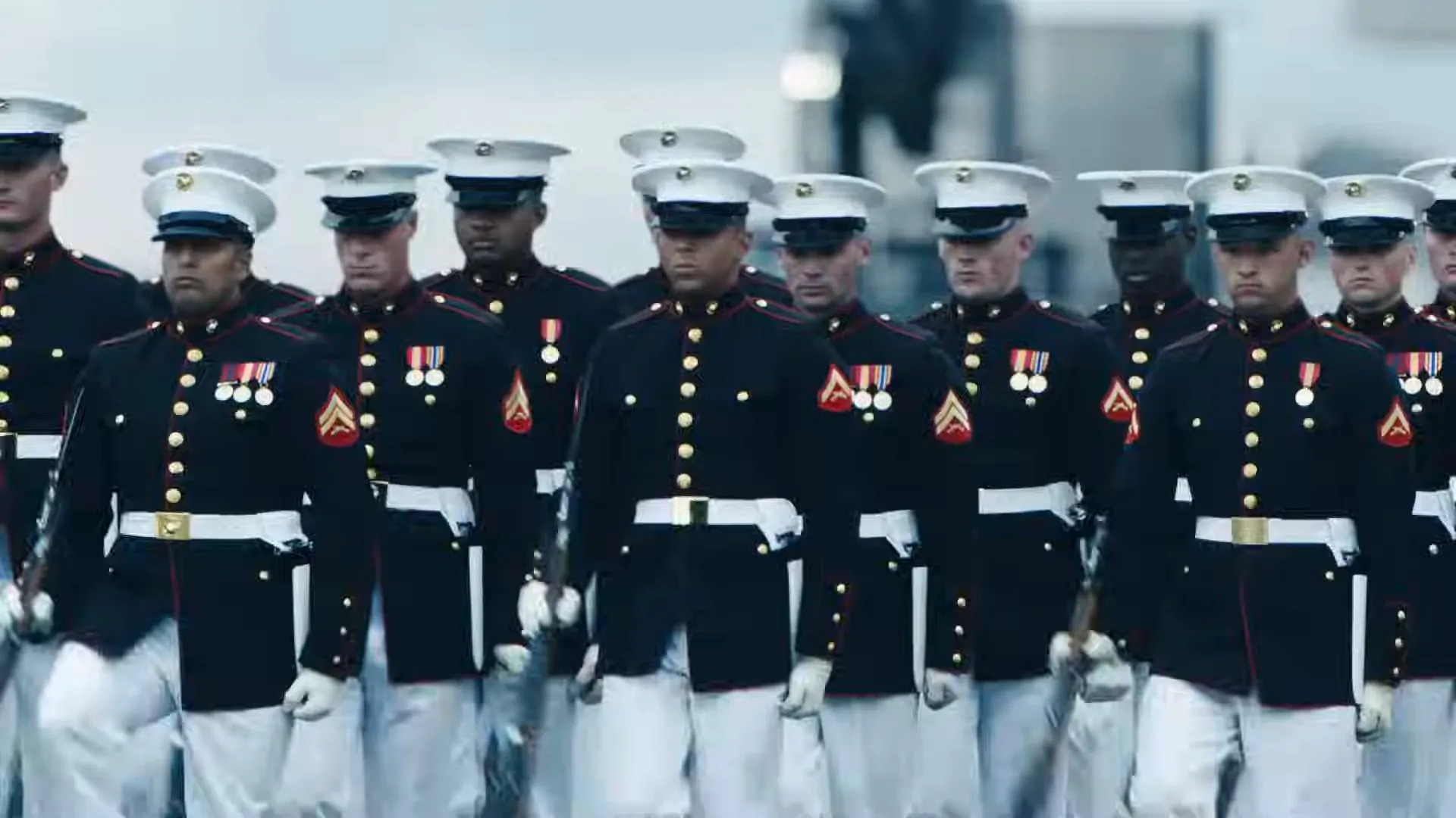 A group of U.S. Marine Corps soldiers in formal uniforms marching in formation with medals on their uniforms