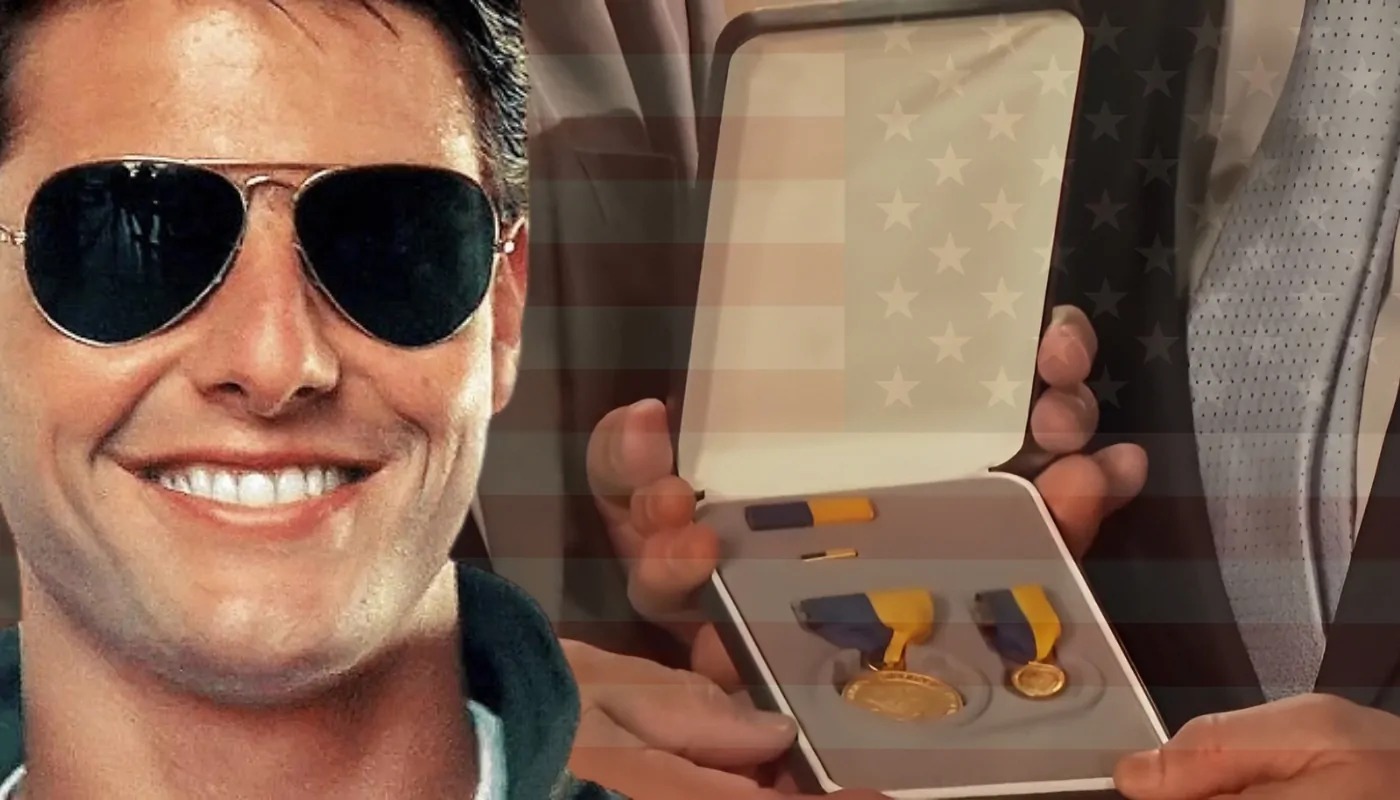 Close-up of a smiling man in aviator sunglasses with a medal case containing gold and blue awards in the background