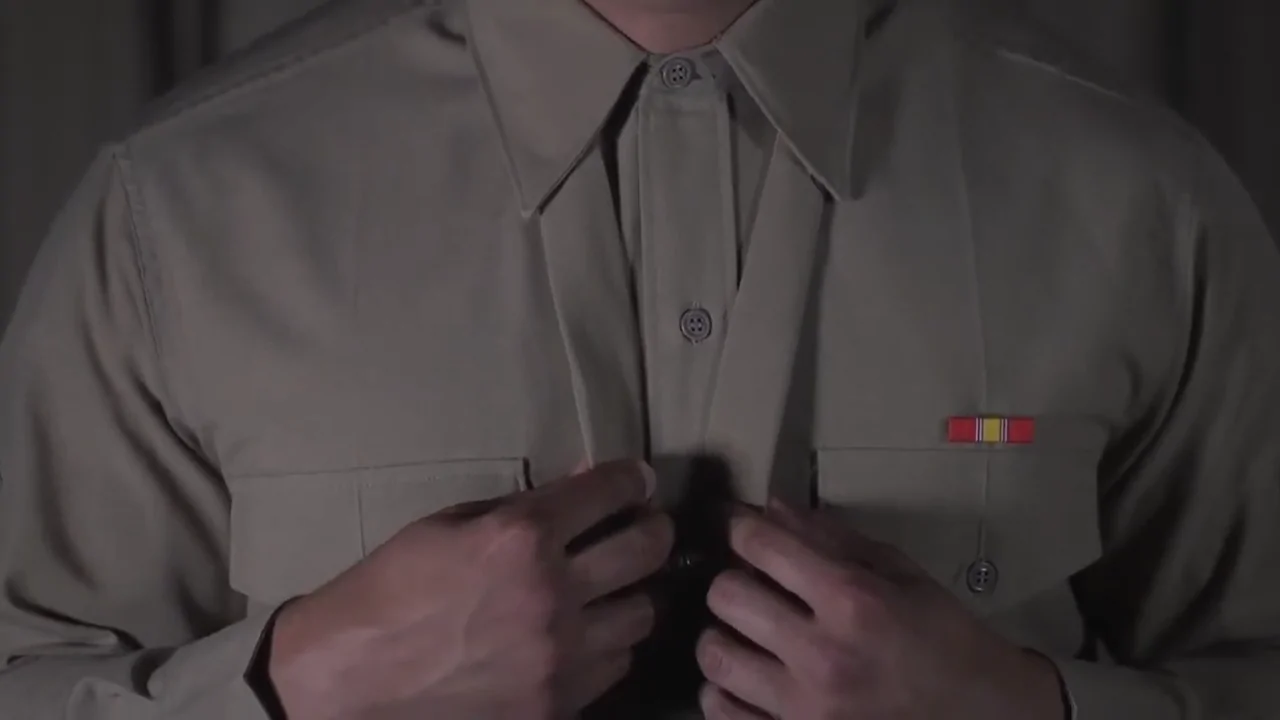 A Close-Up of A Soldier Adjusting Their Army Green Service Uniform Shirt and Neckwear