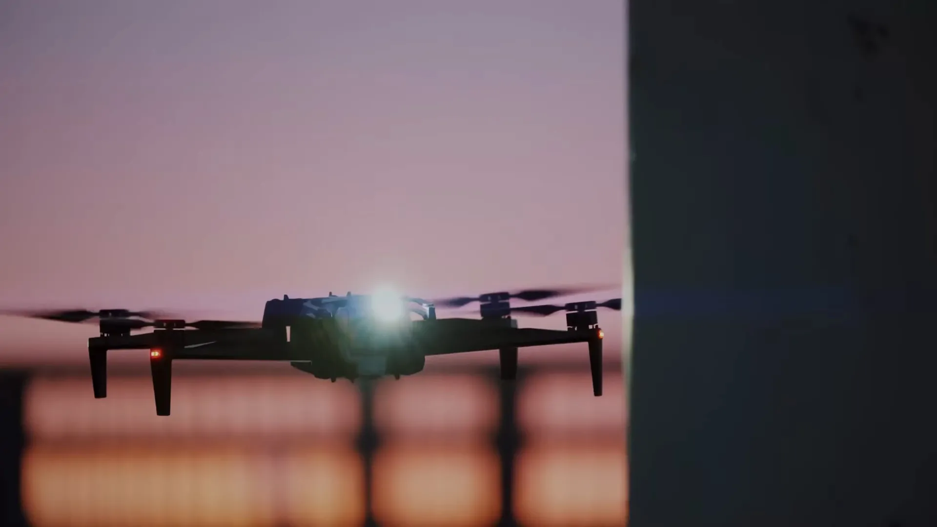 A drone with lights on, flying in a twilight setting with blurred background