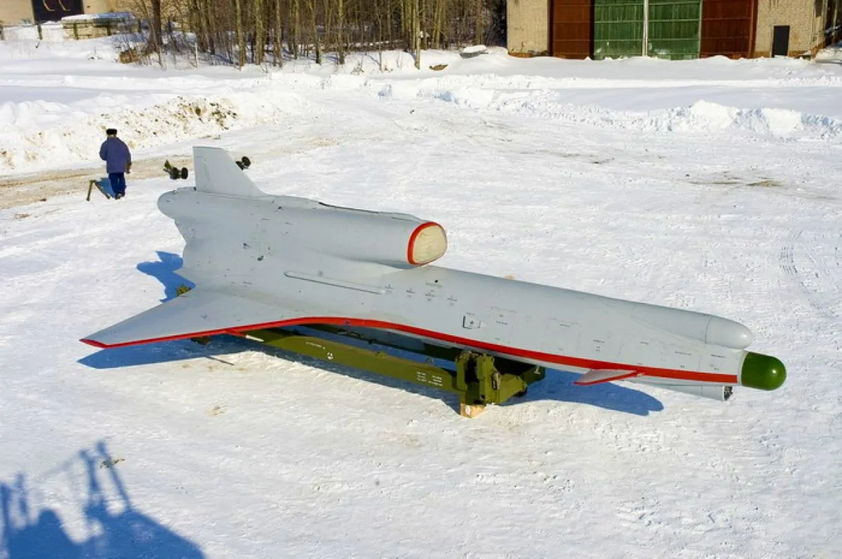 "A Tupolev Tu-300 unmanned aerial vehicle (UAV) on a snowy field, mounted on a transport platform, with a person walking nearby