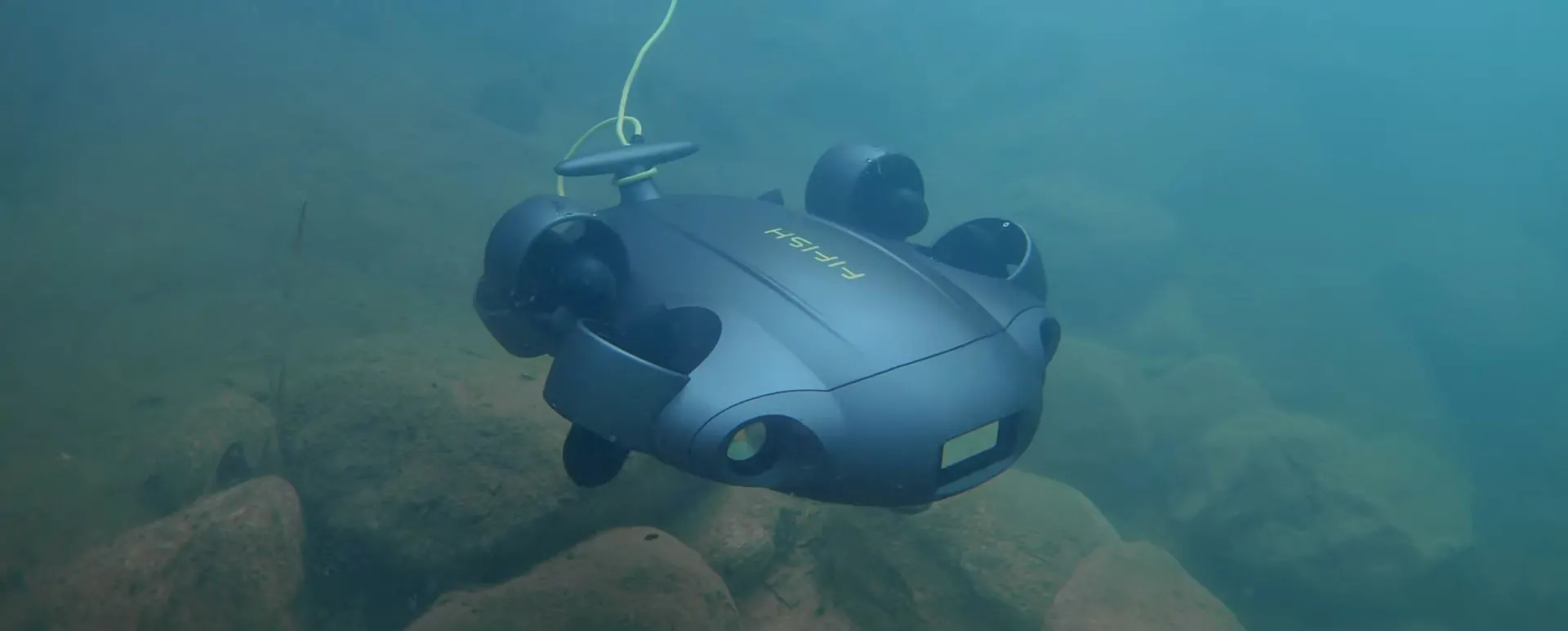 An underwater drone operating near rocky terrain beneath the water