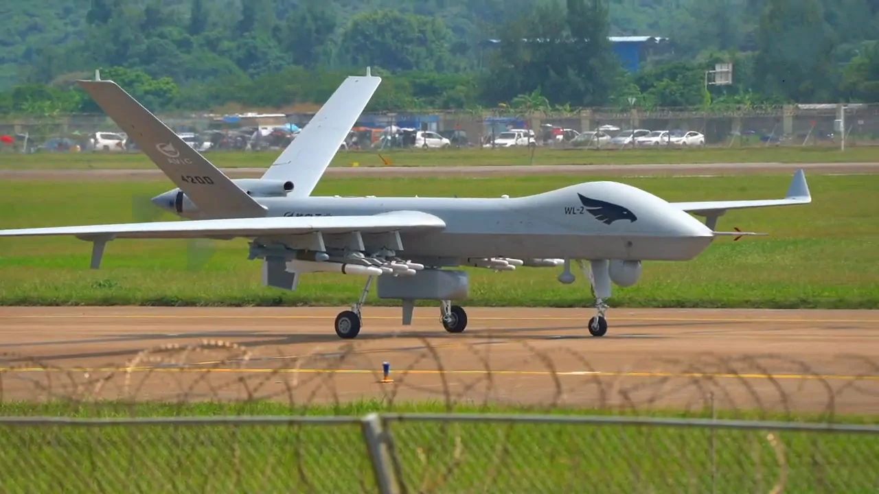 Wing Loong II UAV on a runway with grassy surroundings and a backdrop of trees and buildings