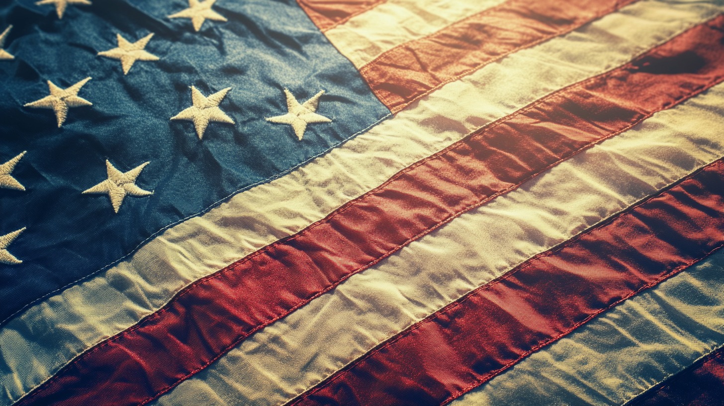 Close-up of a textured American flag with stars and stripes, illuminated by warm sunlight