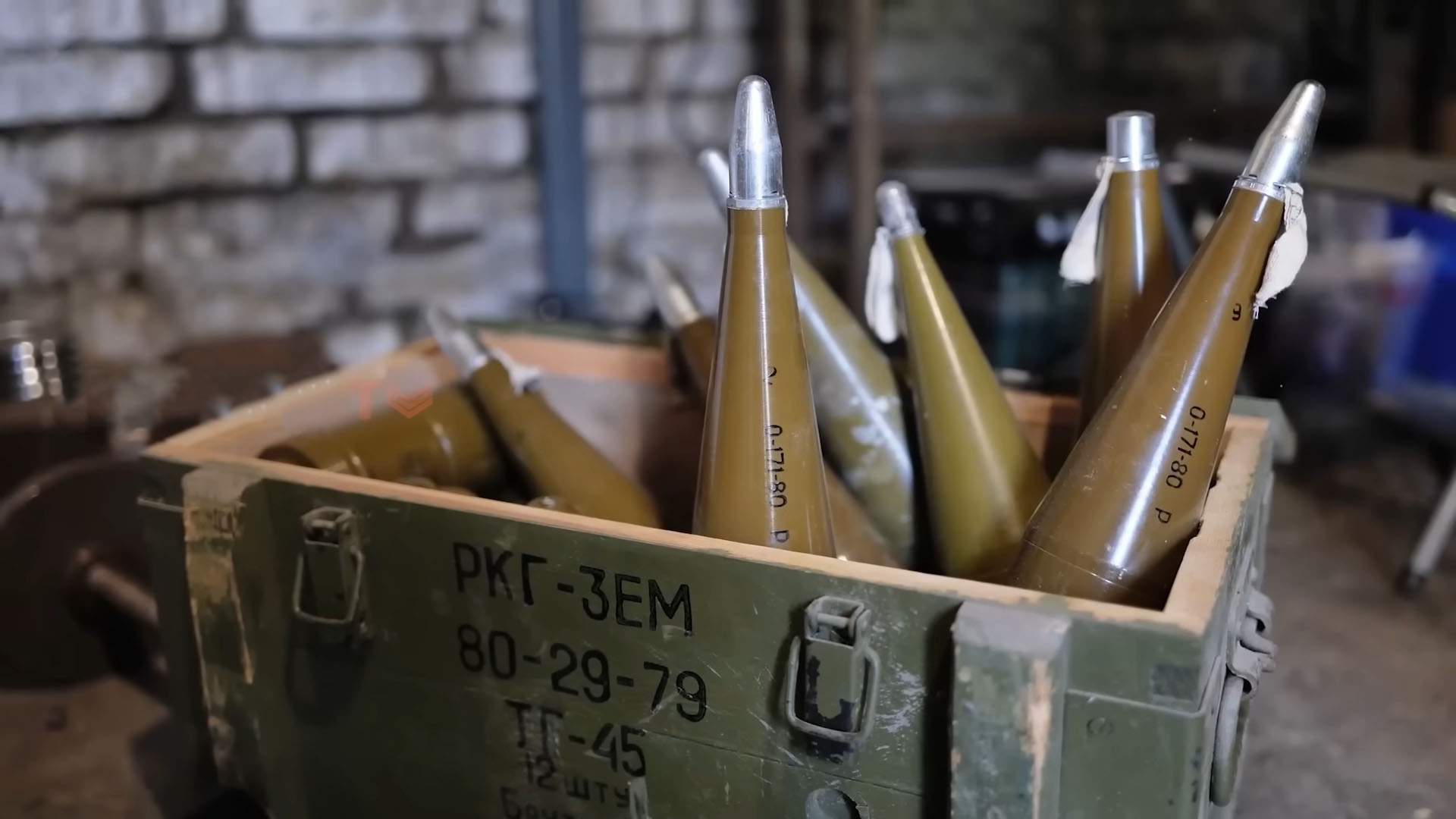 A wooden crate filled with conical military ammunition rounds, stored in a dimly lit warehouse