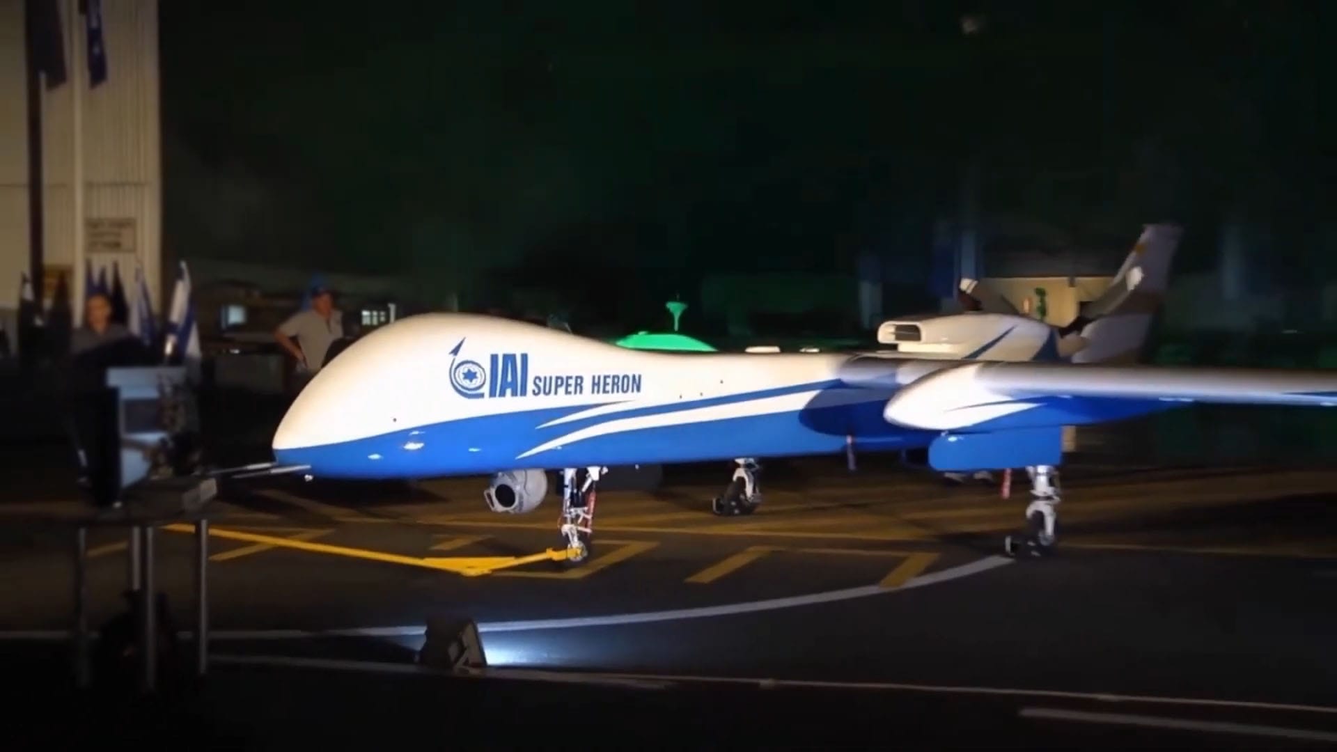 A nighttime image of the IAI Super Heron unmanned aerial vehicle (UAV) on display, painted in blue and white with the Israel Aerospace Industries (IAI) logo