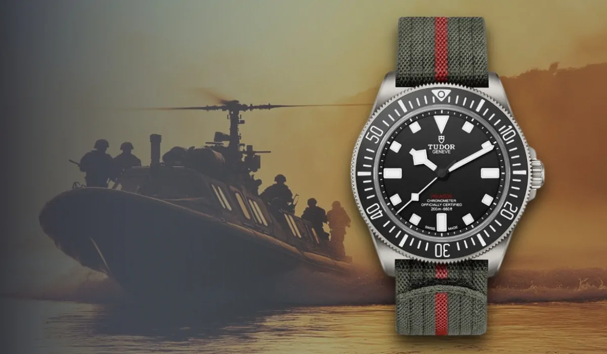 A Tudor Pelagos FXD dive watch with a black dial and a rugged green fabric strap, set against a military boat and helicopter background